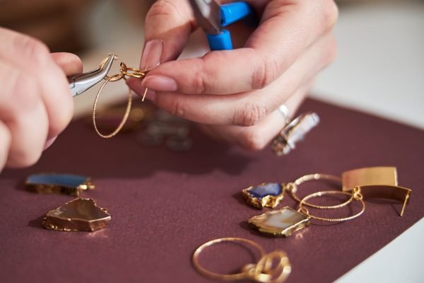 Cropped photo of a craftswoman making a new jewelry item applying two pairs of pliers